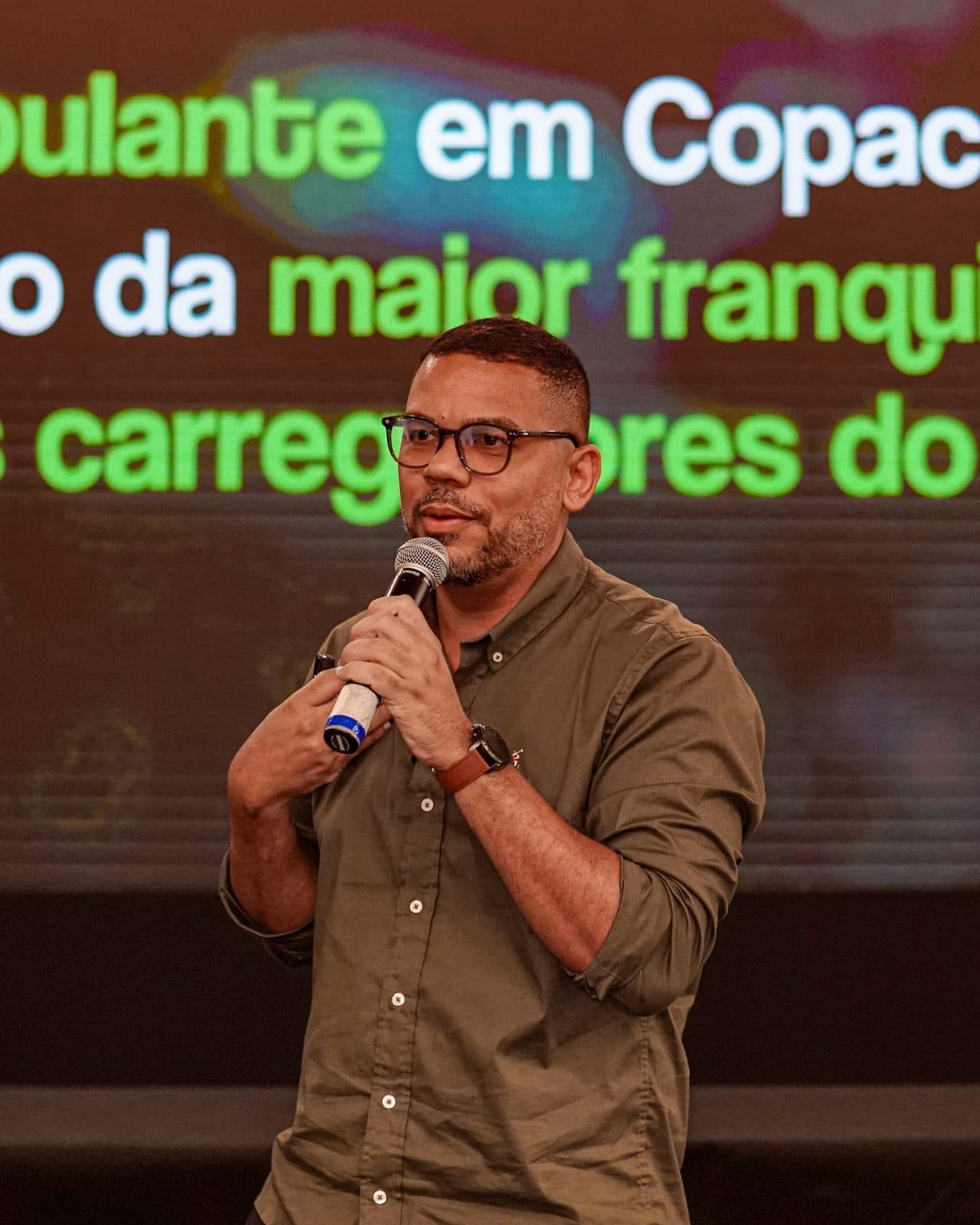 Rafael no palco, com o telão ao fundo citando Copacabana